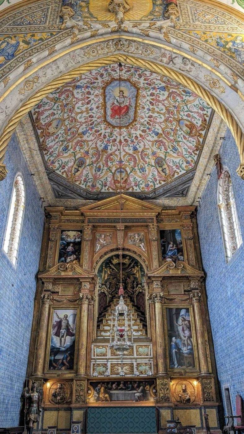 Gilded altarpiece beneath a painted ceiling in a chapel in Coimbra
