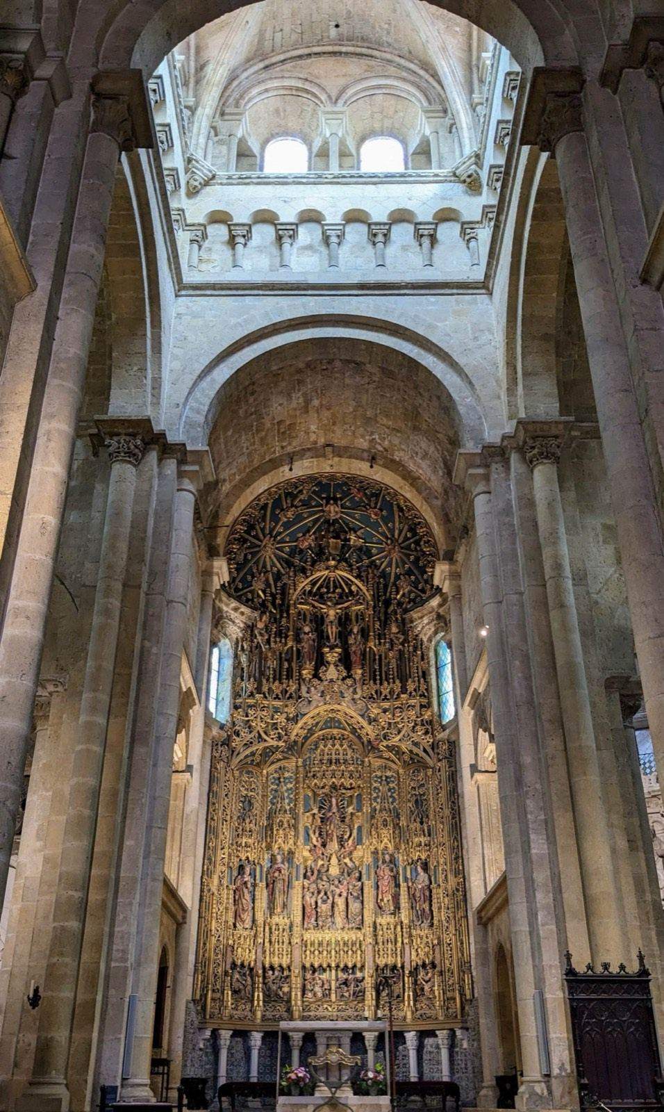Stone nave leading to a gilded altarpiece in a cathedral in Coimbra