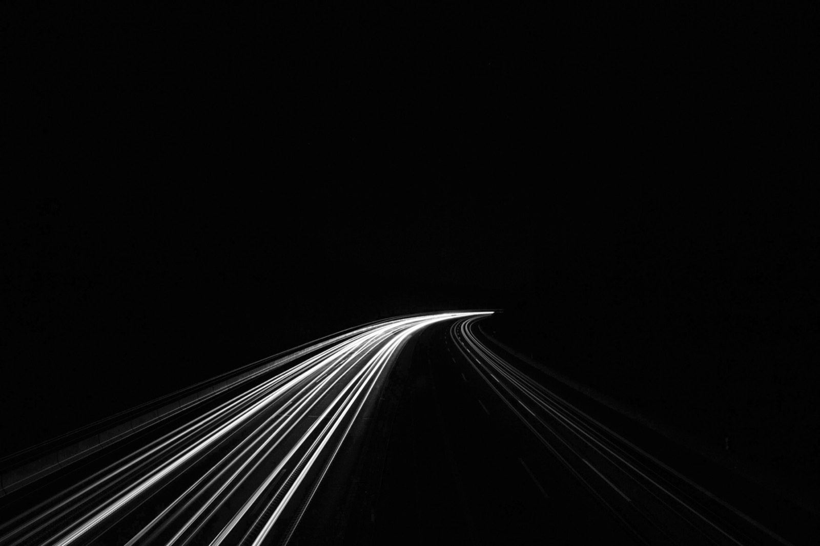 Light trails of cars on a dark road at night