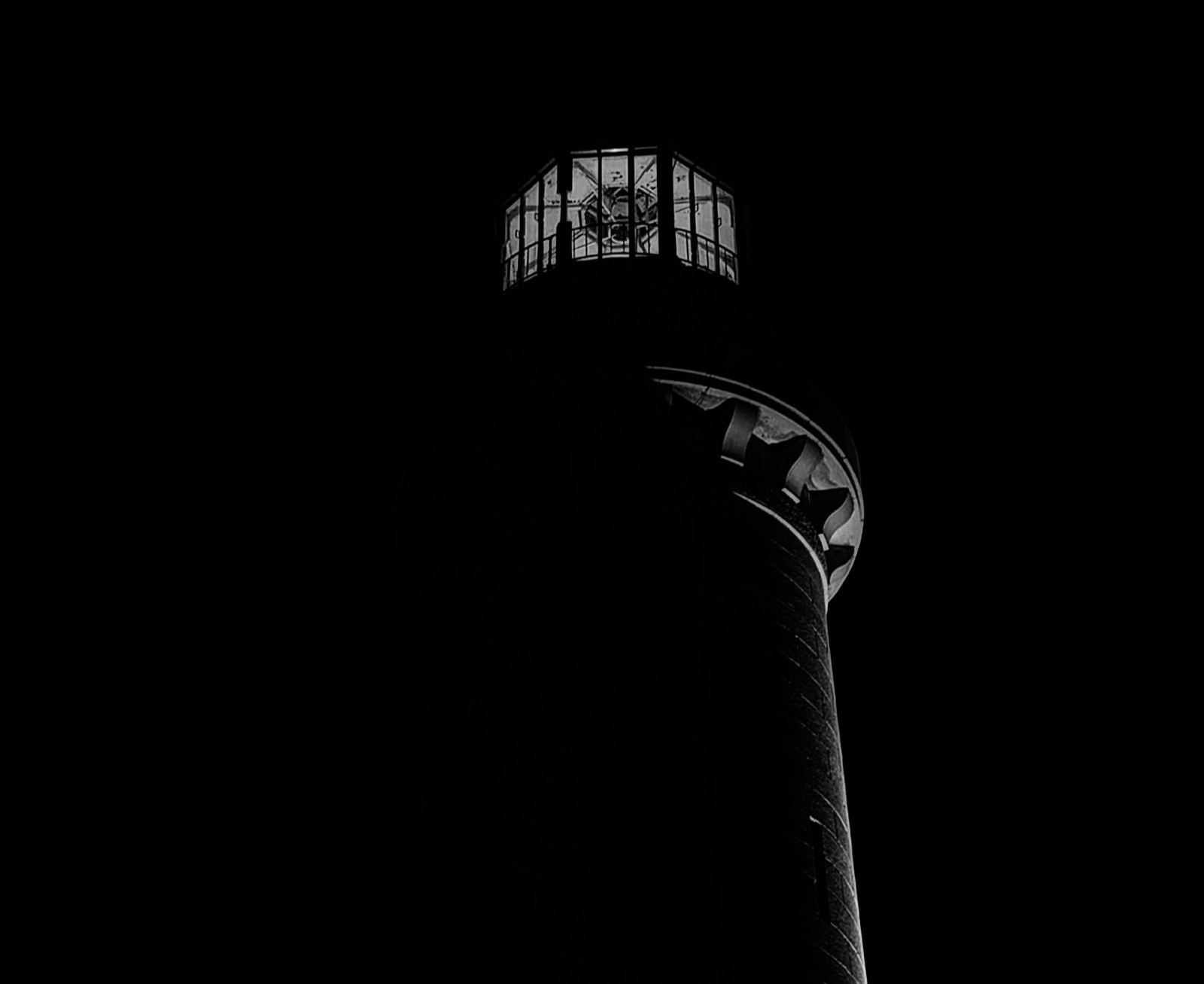 Lit lighthouse lantern against a black night sky in Trieste